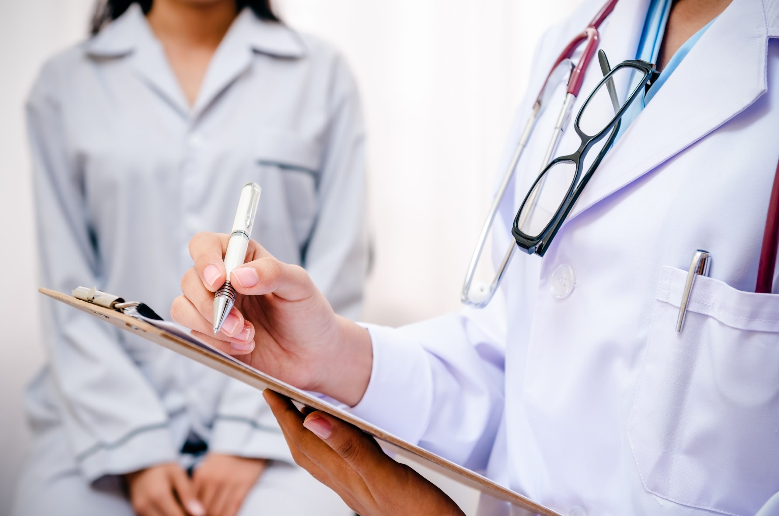 A doctor writing notes during a gynaecologist check-up.